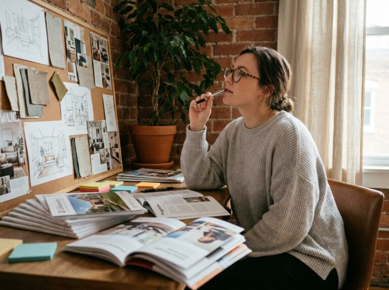Étudiante comparant des brochures de formation en architecture d'intérieur à son bureau